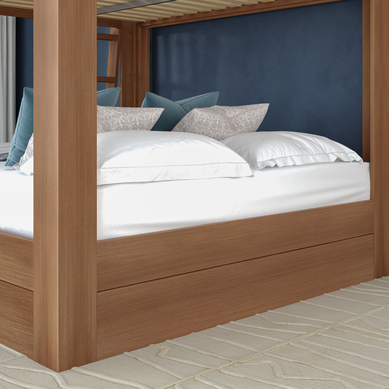 Wooden canopy bed with crisp white linens, patterned and teal accent pillows against a navy blue wall