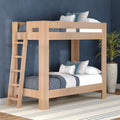 Solid wood twin-over-twin bunk bed with ladder in natural finish, blue bedding and decorative pillows in a modern kids' bedroom with navy textured wall, striped rug and potted plant — space-saving bunk bed design