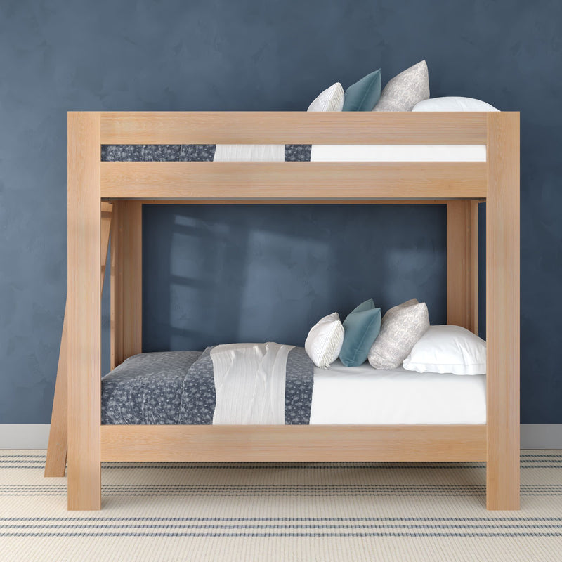 Light wood twin-over-twin bunk bed styled with blue and white bedding and decorative pillows against a navy textured wall in a modern minimalist kids' bedroom with striped rug