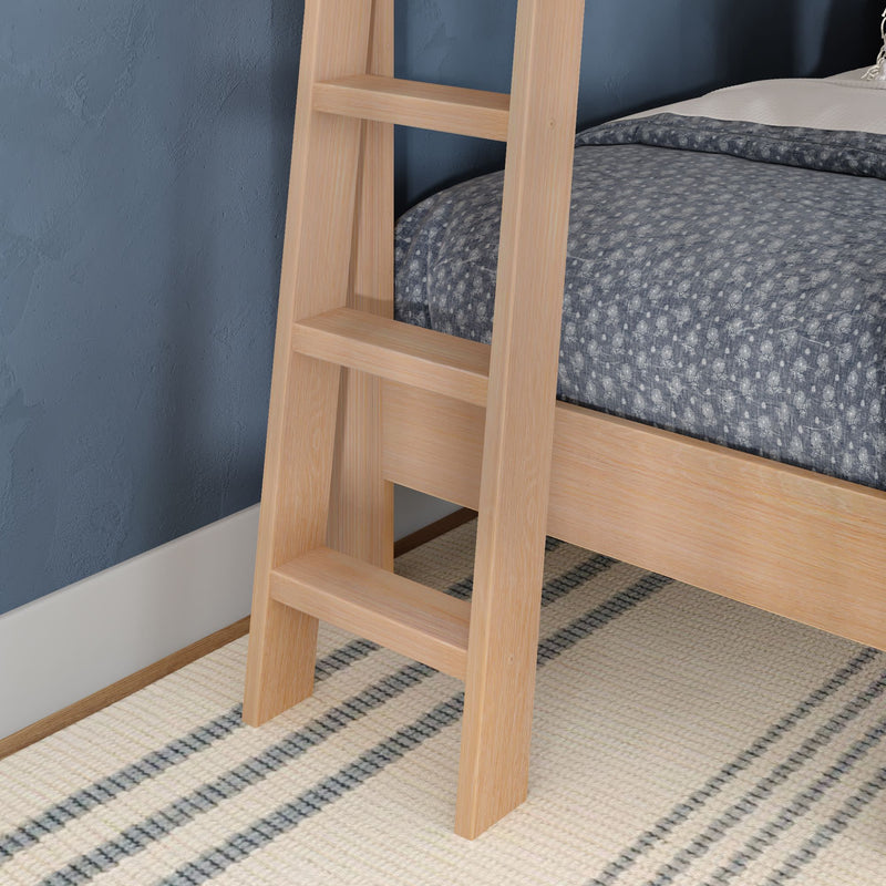 Close-up of light wooden bunk bed ladder beside oak bed frame with blue patterned comforter and striped rug in a modern kids' bedroom