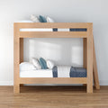 Light wood twin bunk bed with ladder, white and blue bedding and decorative pillows in minimalist kids' bedroom on hardwood floor