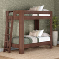 Modern solid wood twin-over-twin bunk bed with ladder, green quilted bedding and neutral pillows in cozy farmhouse bedroom with floral wallpaper and potted plant