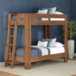Solid wood bunk bed with ladder in modern navy blue bedroom, blue patterned bedding and decorative pillows beside a potted plant