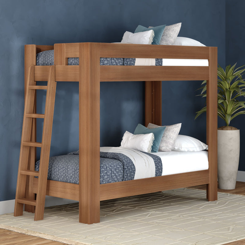 Solid wood bunk bed with ladder in modern navy blue bedroom, blue patterned bedding and decorative pillows beside a potted plant
