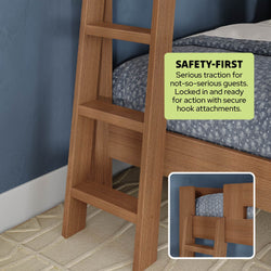 Wooden bunk bed ladder with wide non-slip flat steps and secure hook attachments on oak-finish bed beside blue wall, close-up showing mattress and "Safety-First" traction label