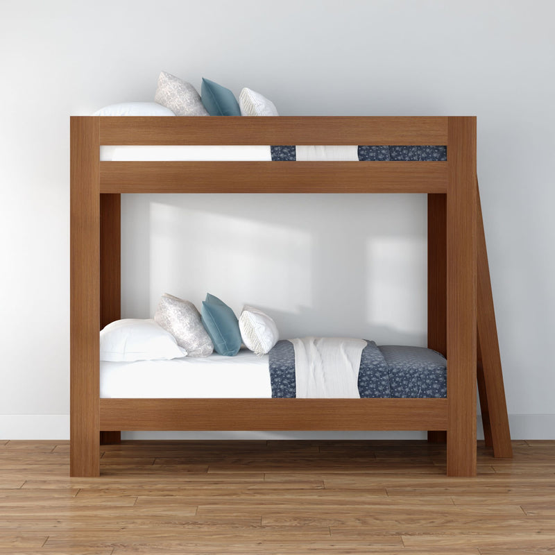 Modern wooden twin-over-twin bunk bed with blue and white bedding, decorative pillows and ladder on hardwood floor in minimalist bedroom