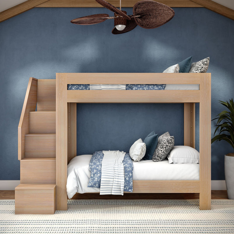 Light wood twin bunk bed with built-in stairs in a modern children's bedroom, blue accent wall, patterned blue-and-white bedding, ceiling fan and potted plant