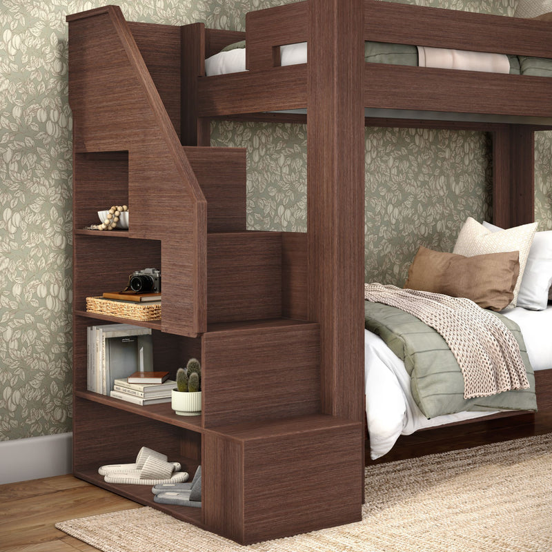 Dark wood space-saving bunk bed with staircase storage and built-in shelving in cozy bedroom with floral wallpaper
