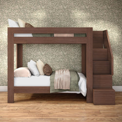 Wooden bunk bed with staircase in cozy bedroom — twin-over-twin bunk with green quilt, knit throw and decorative pillows against floral wallpaper on hardwood floor