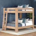 Light wood bunk bed with ladder, blue patterned bedding and teal accent pillows against a navy wall, potted plant and striped rug