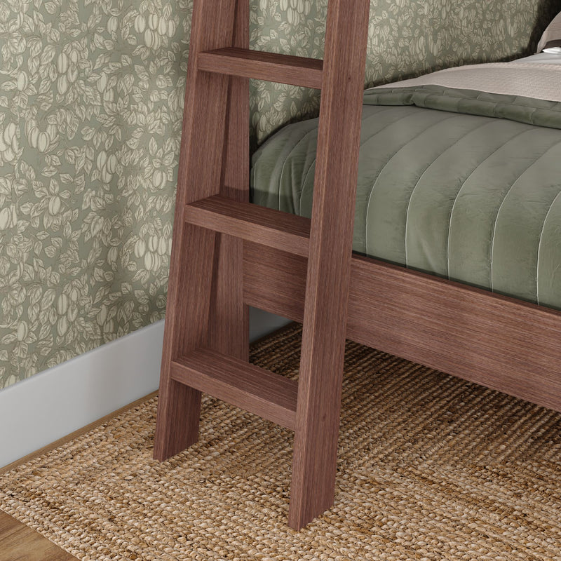 Wooden ladder leaning against walnut bed frame with sage green quilted comforter, botanical floral wallpaper and woven jute rug in a cozy modern farmhouse bedroom