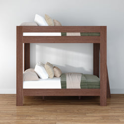 Modern solid wood twin bunk bed with green quilted bedding, neutral throw pillows and hardwood floor in minimalist bedroom