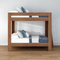 Modern solid wood bunk bed with blue and white bedding in a minimalist room, space-saving contemporary bedroom furniture