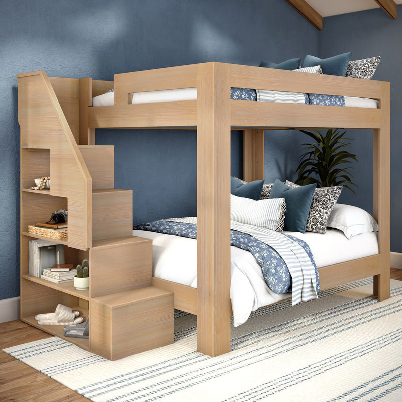 Modern solid wood bunk bed with built-in storage staircase, blue coastal bedding, decorative pillows and rug in a styled kids' bedroom