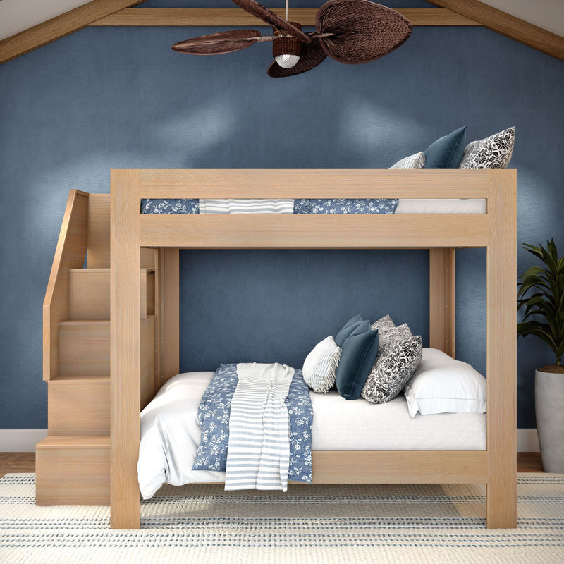 Light oak bunk bed with built-in staircase, blue-and-white patterned bedding and decorative pillows against a navy textured wall in a modern kids' bedroom