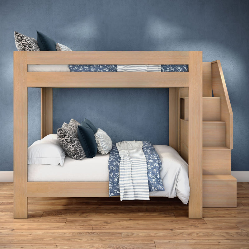 Light wood bunk bed with integrated staircase, navy and white patterned bedding and decorative pillows against a blue accent wall in a modern kids' bedroom with hardwood floors — space-saving loft bed design