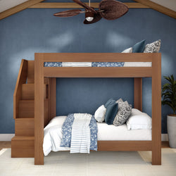 Modern wooden twin-over-full bunk bed with built-in staircase, blue floral and striped bedding, decorative pillows, navy textured wall and ceiling fan