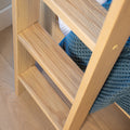 Oak ladder shelf close-up showing natural wood grain and slatted rungs with folded blue knitted blanket, modern home decor storage solution