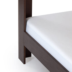 Close-up of dark wood bed frame leg and side rail with white mattress corner, modern platform bed detail optimized for bedroom furniture listings