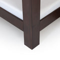 Close-up of dark espresso wood platform bed frame corner with white mattress, modern solid wood bedroom furniture detail