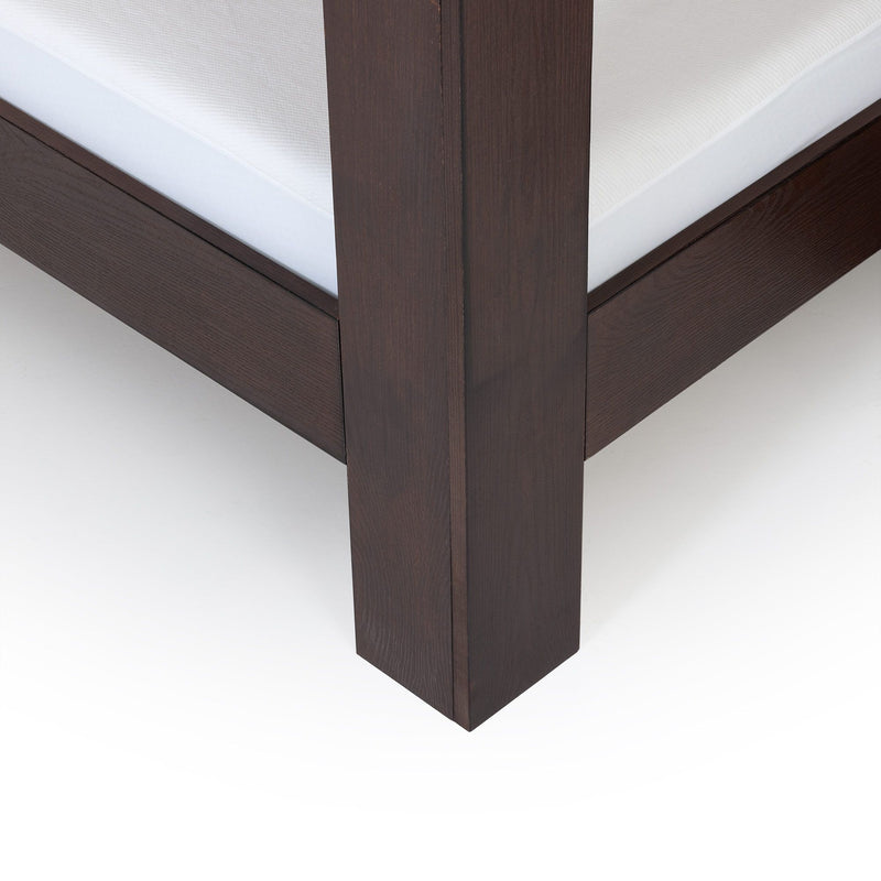Close-up of dark espresso wood platform bed frame corner with white mattress, modern solid wood bedroom furniture detail