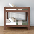 Modern solid wood bunk bed with green and beige bedding in a minimalist bedroom, space-saving loft-style sleeping solution on hardwood floor