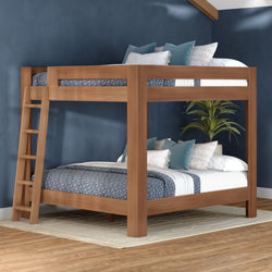 Modern solid wood bunk bed with ladder and blue patterned bedding, accent pillows and indoor plant in a navy, space-saving bedroom