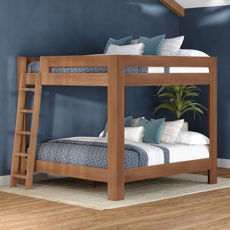 Modern solid wood bunk bed with ladder and blue patterned bedding, accent pillows and indoor plant in a navy, space-saving bedroom