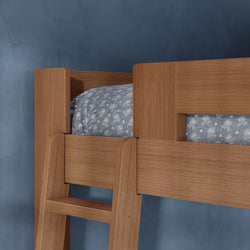 Close-up of a natural oak-finish wooden bunk bed with ladder and blue floral bedding against a textured blue wall, modern kids bedroom design
