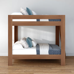 Solid wood twin-over-twin bunk bed with blue and white bedding and decorative pillows in a minimalist bedroom on hardwood floor