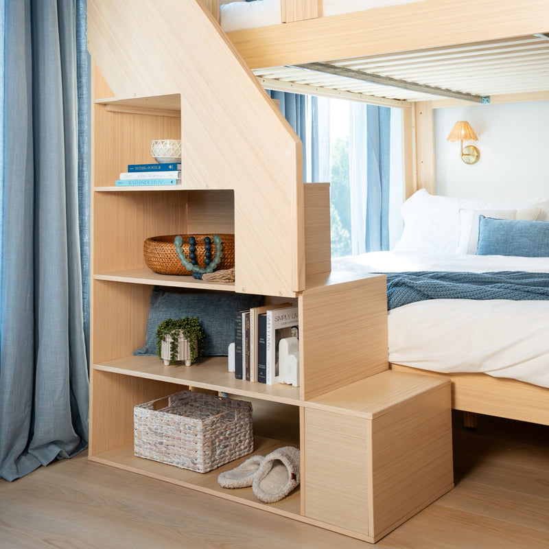 Modern light-wood bunk bed with built-in staircase storage and open shelving, wicker basket, blue curtains and white bedding in a coastal-style bedroom