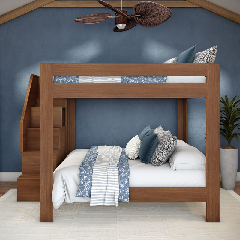 Modern solid wood bunk bed with built-in staircase storage, blue floral bedding and decorative pillows in a coastal-style kids' bedroom.