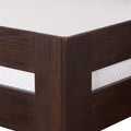 Close-up of dark brown oak bed frame corner with horizontal panels and white textured mattress, modern wooden platform bed
