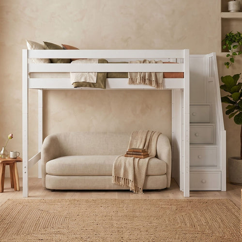 White loft bed with built-in storage stairs over beige sofa in a neutral modern kids' bedroom with woven rug, potted plant and layered textiles.