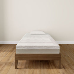Single bed with a comfortable mattress and wooden frame in a minimalist bedroom setting.