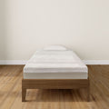 Single bed with a comfortable mattress and wooden frame in a minimalist bedroom setting.