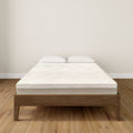 Modern minimalistic bedroom with wooden bed frame and comfortable mattress on hardwood floor.