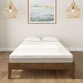 Modern bedroom with minimalist wooden bed frame and plush mattress surrounded by cozy decor and bamboo lighting fixtures.