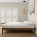 Modern bedroom with a sleek wooden bed frame, minimalist decor, and a comfortable mattress near large French doors.