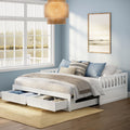 White wooden daybed with underbed storage drawers in a coastal-style bedroom with light blue walls, large window overlooking a lake, woven pendant light, neutral layered bedding and hardwood floors