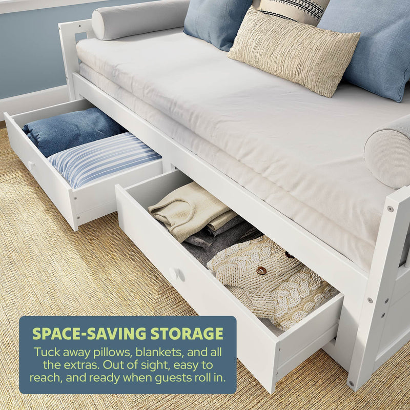 White wooden daybed with pull-out under-bed storage drawers holding pillows and blankets — space-saving guest room sofa bed and bedroom furniture