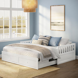 White wooden storage daybed with two under-bed drawers in a coastal-style bedroom with light blue walls, large window, neutral bedding and woven pendant light
