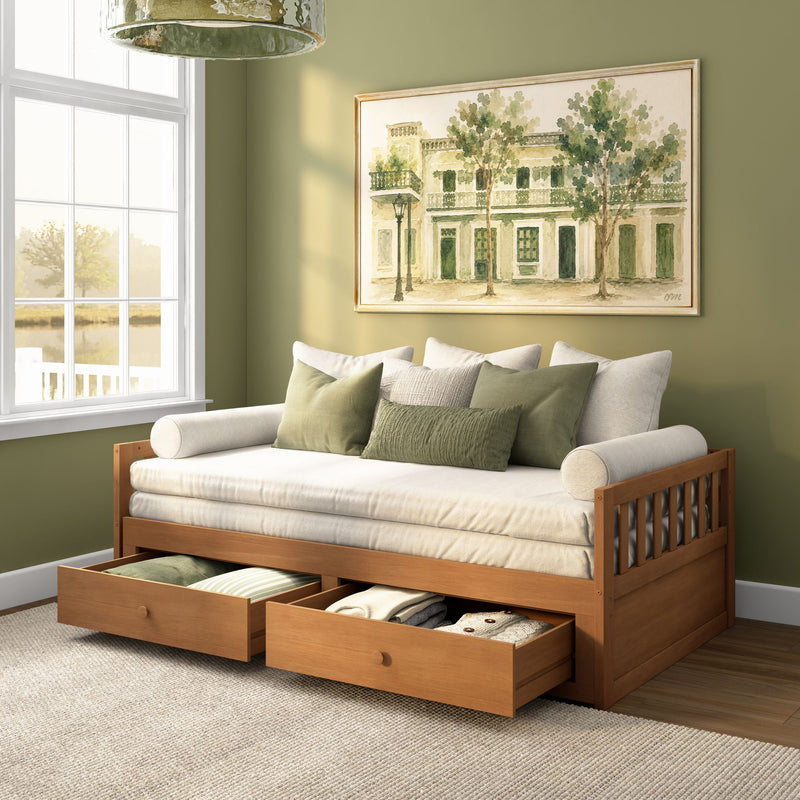 Light-filled guest room with wooden daybed, under-bed storage drawers, green throw pillows and framed watercolor wall art