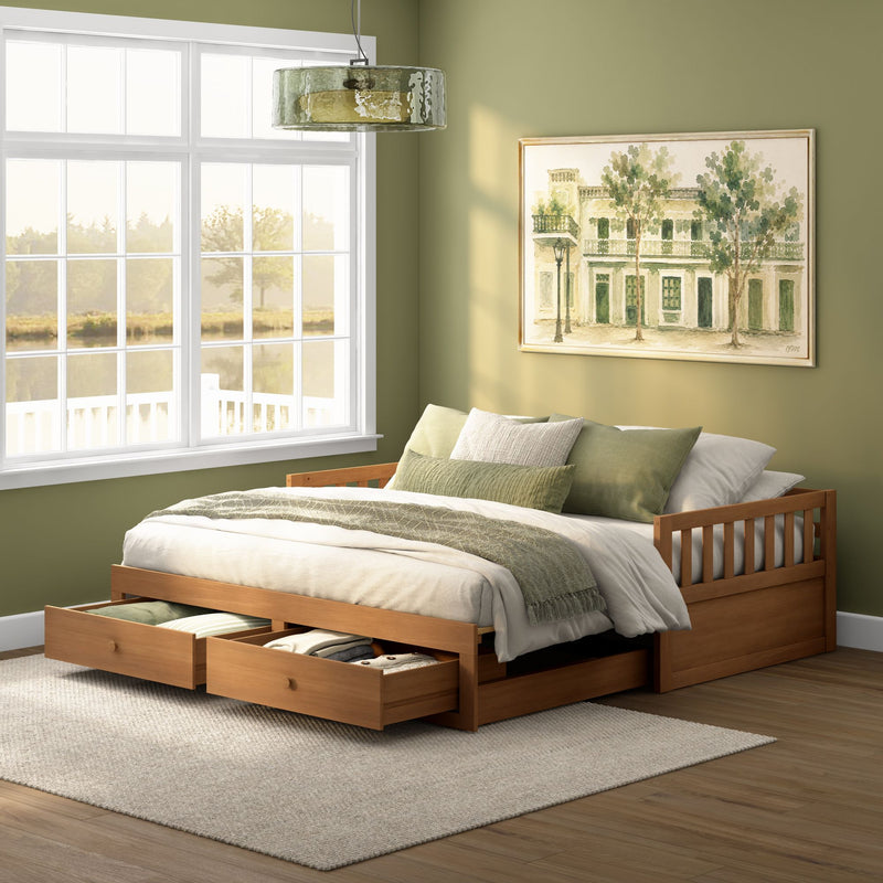 Sunlit green bedroom with wooden storage bed and under-bed drawers, layered neutral bedding, large window and framed watercolor wall art