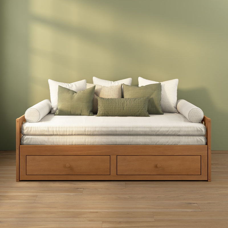 Wooden daybed with storage drawers, cream cushions and olive-green throw pillows against a sage-green wall in a minimalist cozy living room