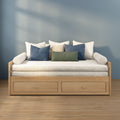 Scandinavian daybed with light wood frame, beige linen cushions and blue and green accent pillows against a soft blue wall