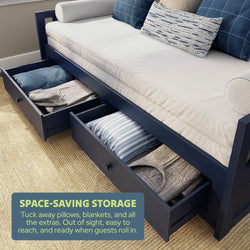 Navy daybed with open under-bed storage drawers holding pillows and blankets, a space-saving guest room storage solution