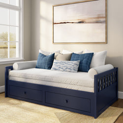 Navy blue wooden daybed with under-bed storage drawers, white mattress and blue patterned throw pillows in a bright coastal-style bedroom