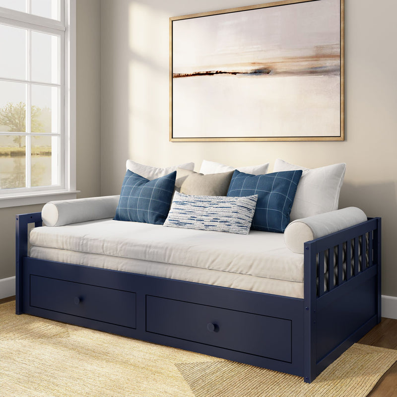 Navy blue wooden daybed with under-bed storage drawers, white mattress and blue patterned throw pillows in a bright coastal-style bedroom