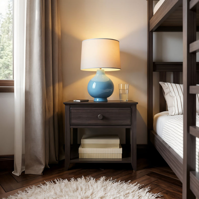 Cozy bedroom corner with a wooden nightstand, blue table lamp, and soft ambient light.